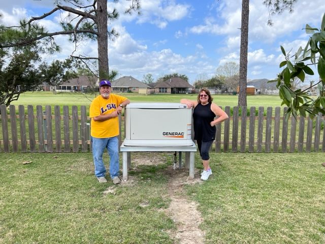 Homeowners standing beside their installed Generac generator in a backyard.