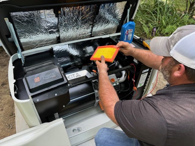 Technician replacing an air filter inside an open Generac generator.